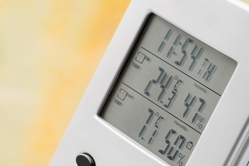Wall Mural - Weather station device with weather conditions inside and outside. Background of a window with raindrops. Yellow background, golden autumn. Selective focus