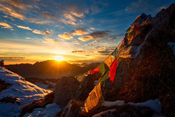 flags of tibetan prayers in the mountains with the colors of a warm sunset