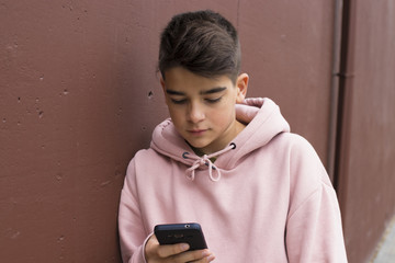 child with the mobile phone on the wall of the city street, teenagers