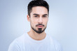 © zinkevych - Calm. Bearded handsome young man looking calm and peaceful while standing against the blue background and looking straight