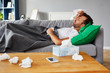 Sick man with fever lying on couch at home