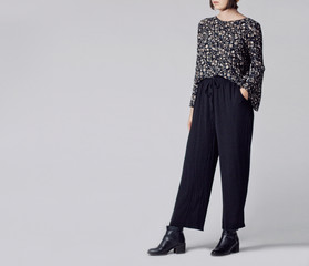 woman wearing stylish outfit with black patterned blouse, black high-waisted wide leg trousers and b