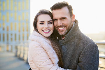 Portrait of happy couple hugging outdoors during sunny winter day