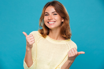 Wall Mural - Smiling woman in sweater showing thumbs up at the camera