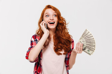 Wall Mural - Happy surprised ginger woman in shirt talking by smartphone