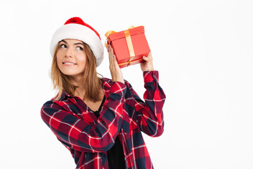 Poster - Pleased brunette woman in shirt and christmas hat holding gift