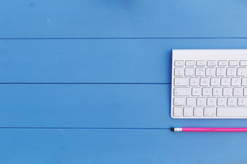 Wall Mural - Computer keyboard and pencil with copy space on blue office desk