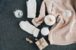 Women's winter clothes look on grey plaid. Warm beige sweater and white knitted mittens, gift box and glass balls. Christmas fashion composition. Flat lay, top view.