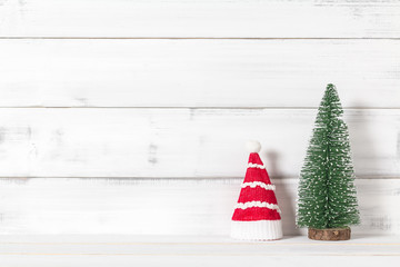 Santa claus hat with christmas tree on white wood over white rustic background with copy space for text