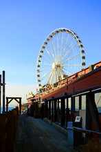 A Ferris Wheel In Seattle, Washington Seen From A Little Wooden Pier  At The City Waterfront