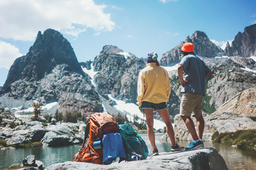 Wall Mural - Young active backpackers couple rock climbing together in stunning mountain wilderness near the snowy lake. Resting and looking at breathtaking natural landscape