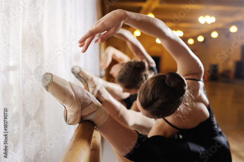 Fotomural three young cute ballerinas perform exercises on a choreographic machine or barr