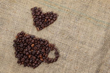 Wall Mural - Roasted coffee beans placed in the shape of a cup and placed on sackclothe