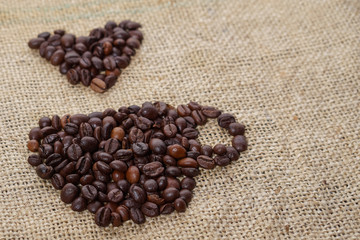 Wall Mural - Roasted coffee beans placed in the shape of a cup and placed on sackclothe