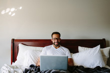 Black man working in bed with laptop computer