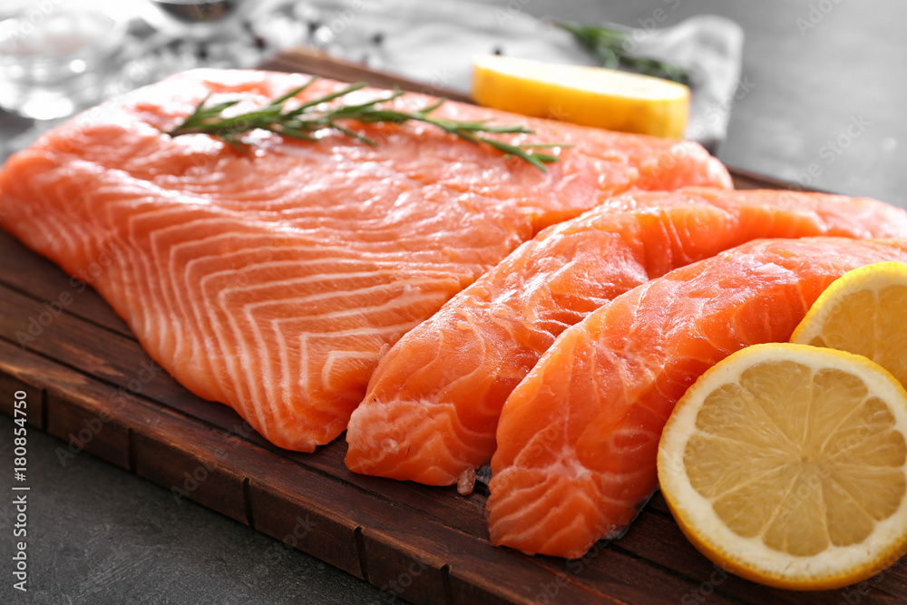 Fresh raw salmon fillet and rosemary on board, closeup