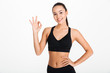 © Drobot Dean - Smiling young sports lady showing okay gesture.