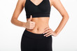 © Drobot Dean - Cropped picture of young sports woman showing thumbs up.