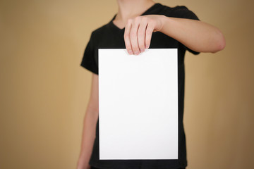 Wall Mural - Man in black t shirt holding blank white A4 paper. Leaflet presentation. Pamphlet hold hands. Man show clear offset paper. Sheet template.