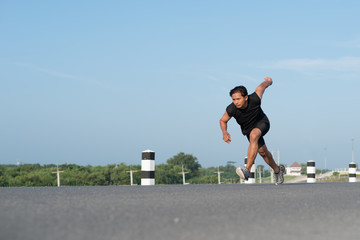 Asia young man running in the time during sunrise on dam road exercise.Healthy lifestyle