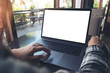 © Farknot Architect - Mockup image of business woman using and touching laptop with blank white screen on wooden table in cafe