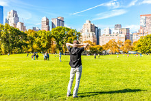 Back Closeup Of One Happy Young Man With Hands Behind Head, Standing In Central Park In New York City During Sunny Autumn Day With Skyscrapers Buildings And People