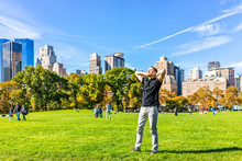 Closeup Of One Happy Young Man With Raised Hands In Central Park In New York City During Sunny Autumn Day With Modern Skyscrapers Buildings And People
