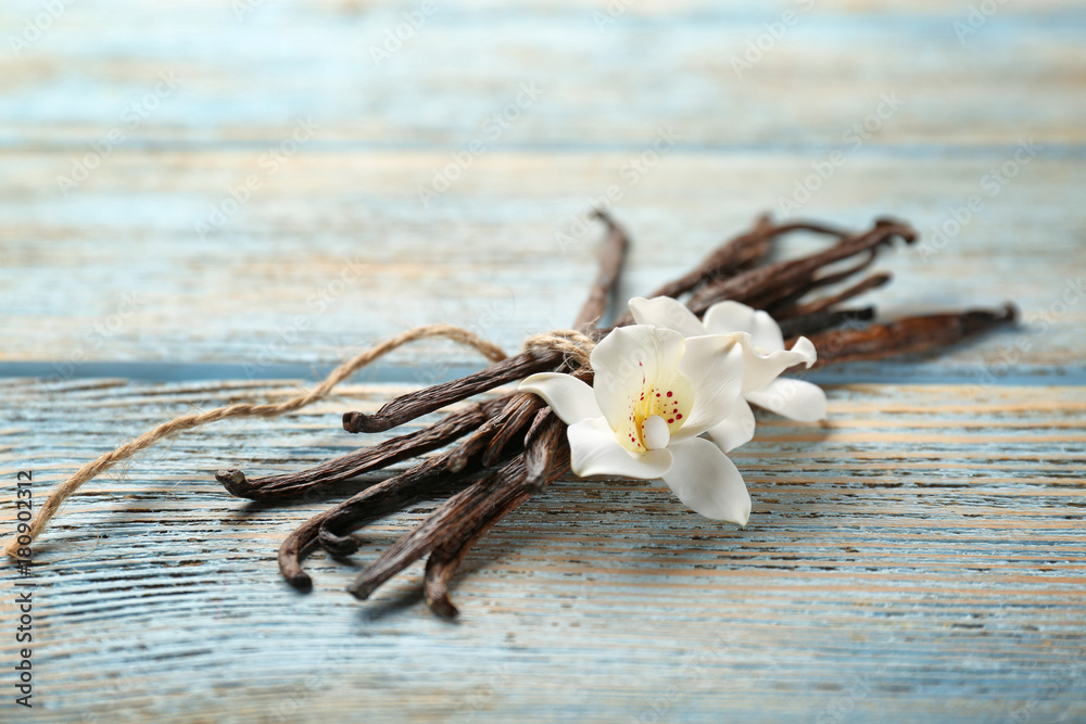 Dried vanilla pods and flowers on wooden background