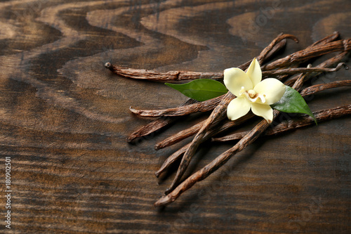Fotomural Dried vanilla pods and flower on wooden background
