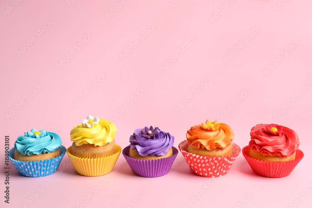 Tasty colorful cupcakes on color background