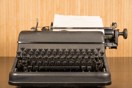 Old typewriter with blank paper on wooden table