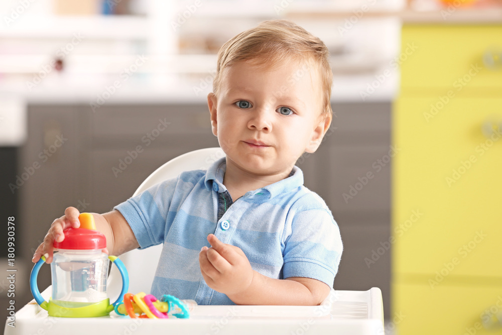 Adorable baby sitting in highchair at home