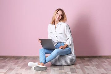 Wall Mural - Young woman with laptop against pink wall