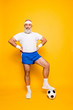© deagreez - Full length of modern cool funny competetive pensioner, leader, champion with his foot on a ball. Bodycare, healthcare, weight loss, pride, strength, leadership, motivation, authority, gym