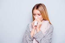Closeup Portrait Of Beautiful Charming Attractive Woman Sneezing In A Tissue Blowing Her Runny Nose, Having A Cold Standing Over Grey Background