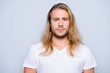 © deagreez - Portrait of handsome young serious confident young guy with blonde long hair in white tshirt, isolated on grey background