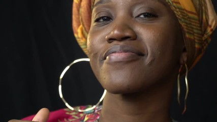 beautiful african woman in national clothes with gold earrings in ears dancing in studio, slow motio