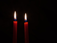 Two Red Candles With Nice Flames Against A Black Background.