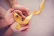 adult and child hands holding yellow gold ribbon, Sarcoma Awareness, Bone cancer, childhood cancer awareness, world suicide prevention day, September Yellow