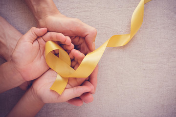 adult and child hands holding yellow gold ribbon, sarcoma awareness, bone cancer, childhood cancer a