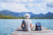 summer travel, young romantic man tourist wanderlust sitting on wooden pier