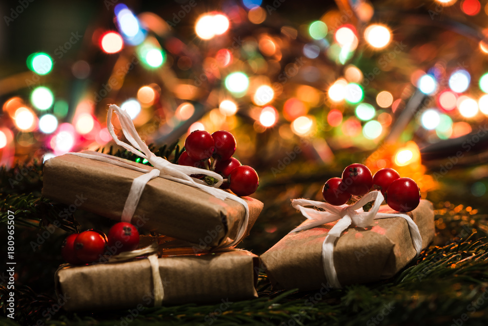фотография Christmas gift in rustic style and colorful lights blurred in the background