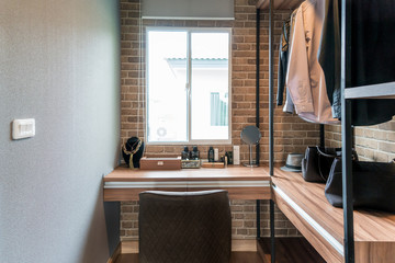 Room with wooden shelves and dresses hanging under the rack, there are garment baskets with drawers.