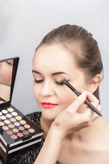 Make-up artist doing eye makeup, close-up. A palette of eye shadows in the hands of a make-up artist