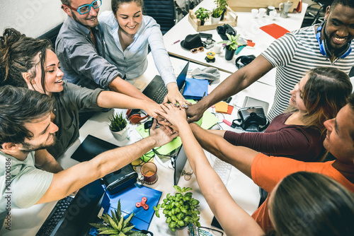 Fotografía Young employee startup workers group stacking hands at urban studio during entre