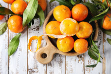Ripe Organic Clementines Or Tangerines With Leaves On Wood Serving Board Over White Wooden Plank Table As Background. Top View, Space. Healthy Eating