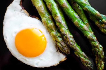 Wall Mural - Fried egg and roasted fresh asparagus in black plate