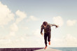 © Connect Images - Young man running along sea wall, front view
