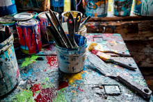 Paint Brushes And Pots Of Paints On Workshop Table