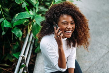 Portrait of smiling curly hair woman talking on phone.